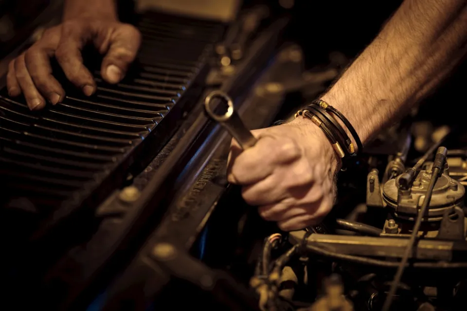 A mechanic adjusts an engine.